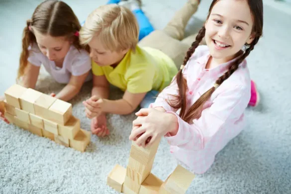 A girl and boy are playing, and an older girl is smiling in the kindergarten